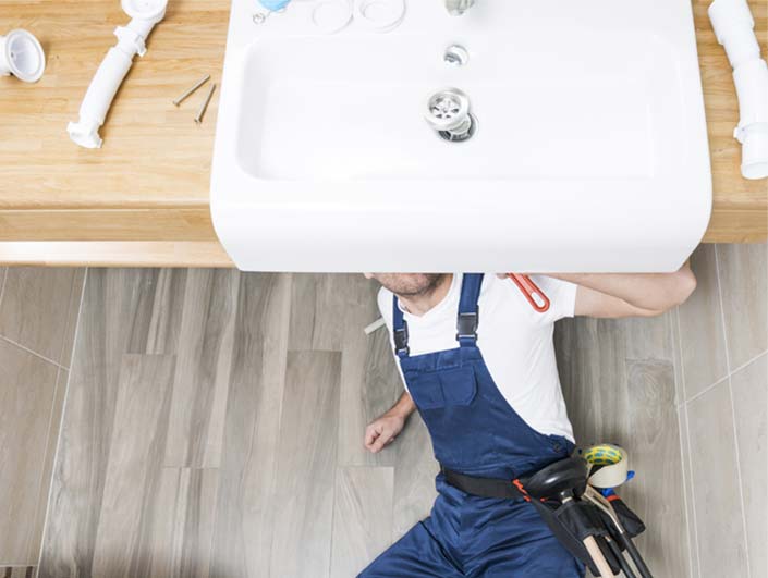 Plombier qui travaille sous lavabo